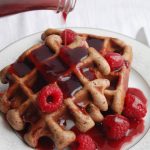 Chocolate waffles on plate with raspberry sauce.