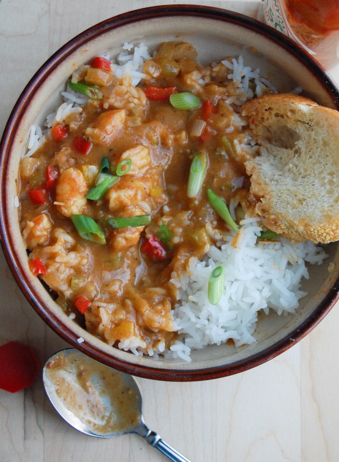 Bowl of shrimp etouffee with rice and a piece of bread with spoon