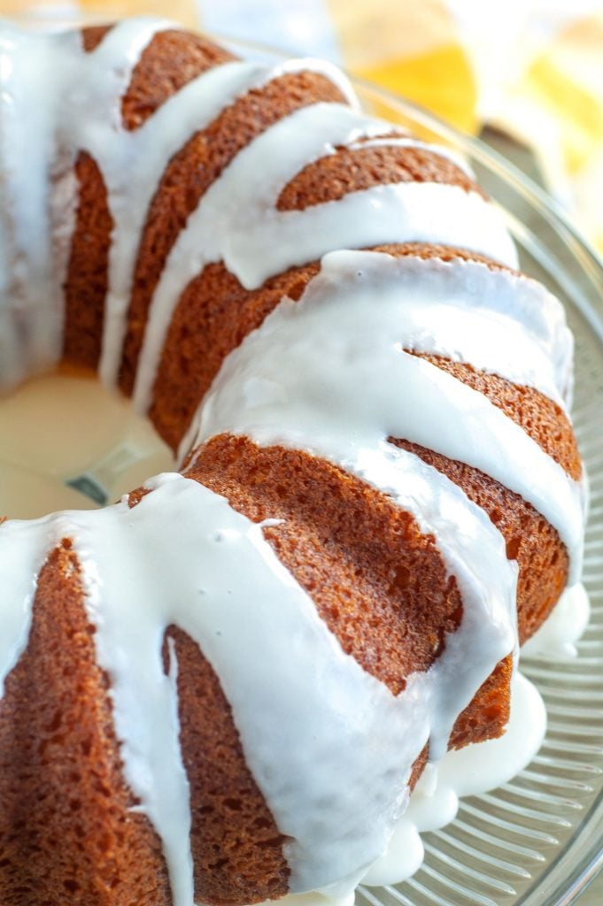 Half of a Apricot Nectar Cake on a cake plate with yellow dish towel in the background