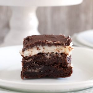Brownie square with cream on plate.