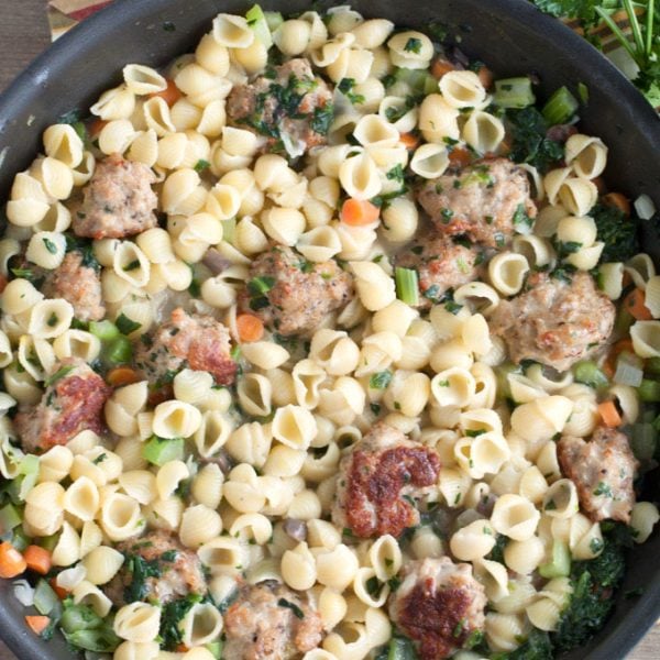 Mini pasta shells with meatballs in a skillet.