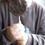 Kid holding chocolate covered apple slice.