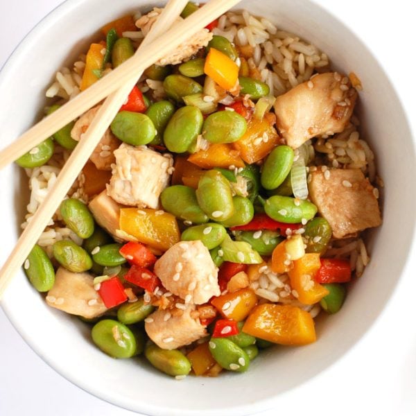 Chicken and edamame in bowl with chopsticks.