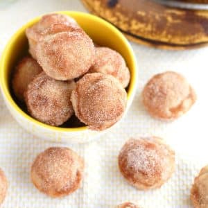 Donut holes in bowl with bananas.