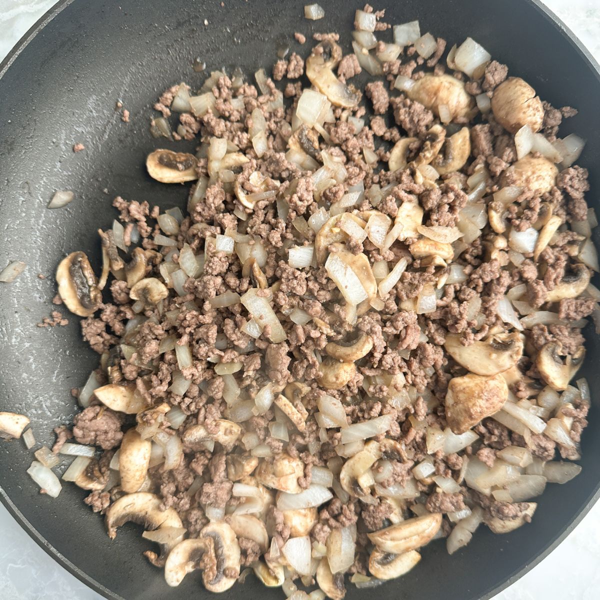 Skillet with ground beef, onions, and mushrooms. 