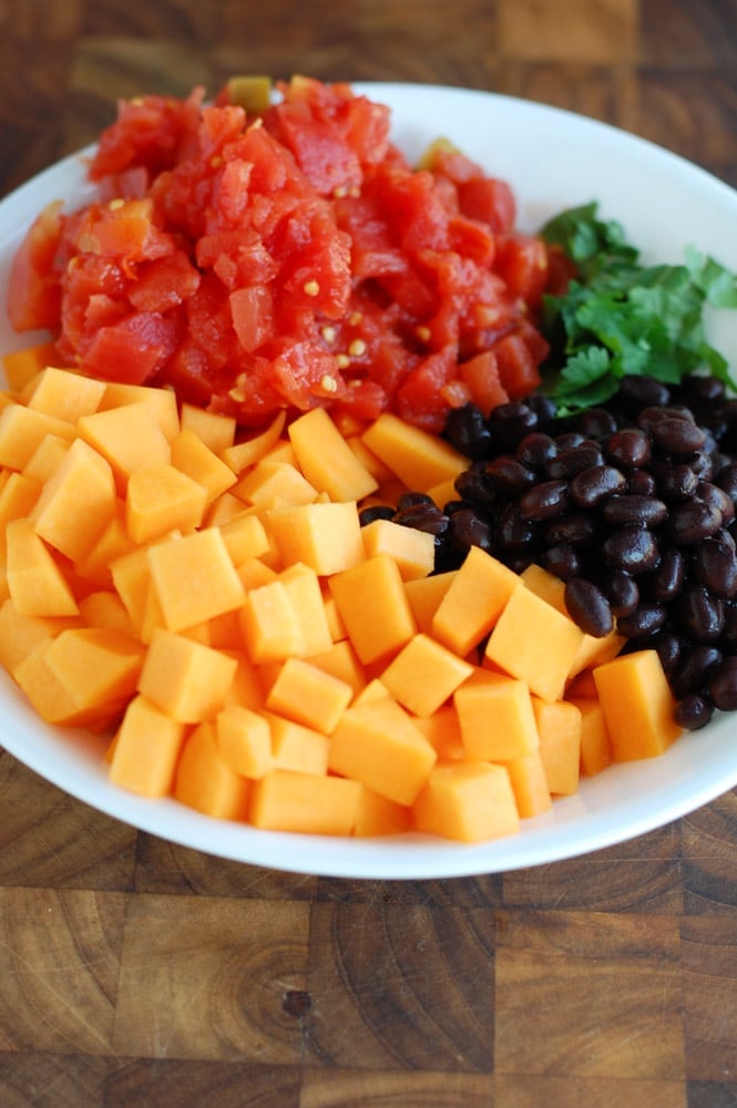 bowl with diced butternut squash, rotel tomatoes, black beans and cilantro