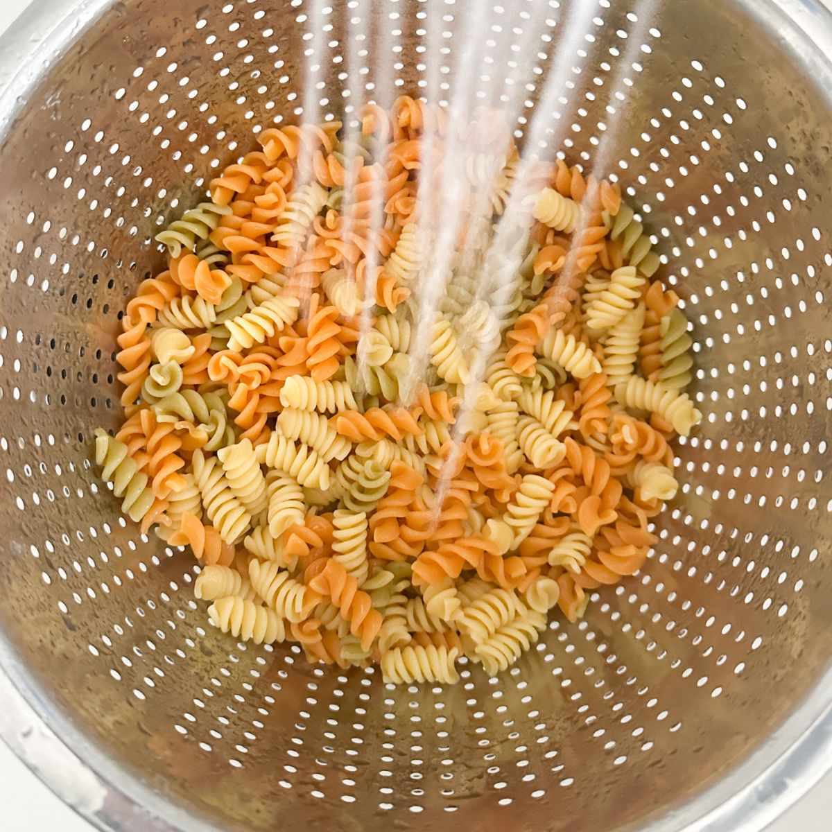 Colander with pasta and running water. 