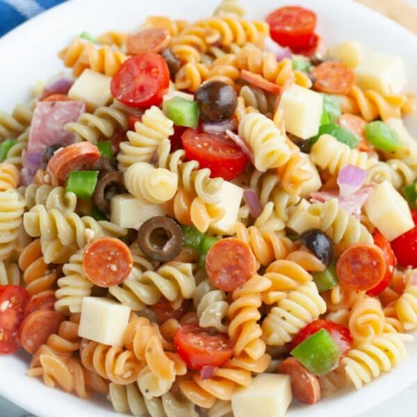 Bowl of pasta salad with pepperoni, tomatoes, and cheese.