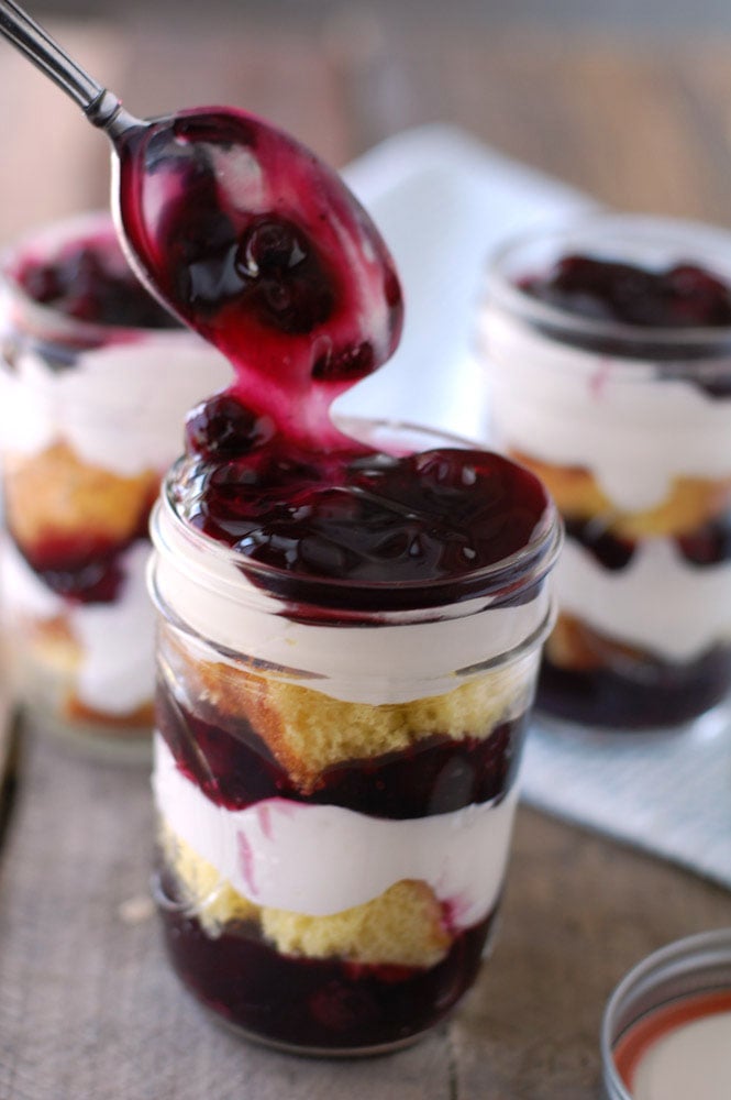 Blueberry Trifle layers of lemon cake, blueberry pie filling, and cream are assembled in Mason jars to make a delicious and portable dessert.