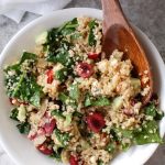 Bowl with quinoa, cherries, spinach and a wooden spoon.