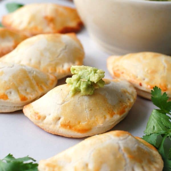 Several empanadas on a table with guacamole.