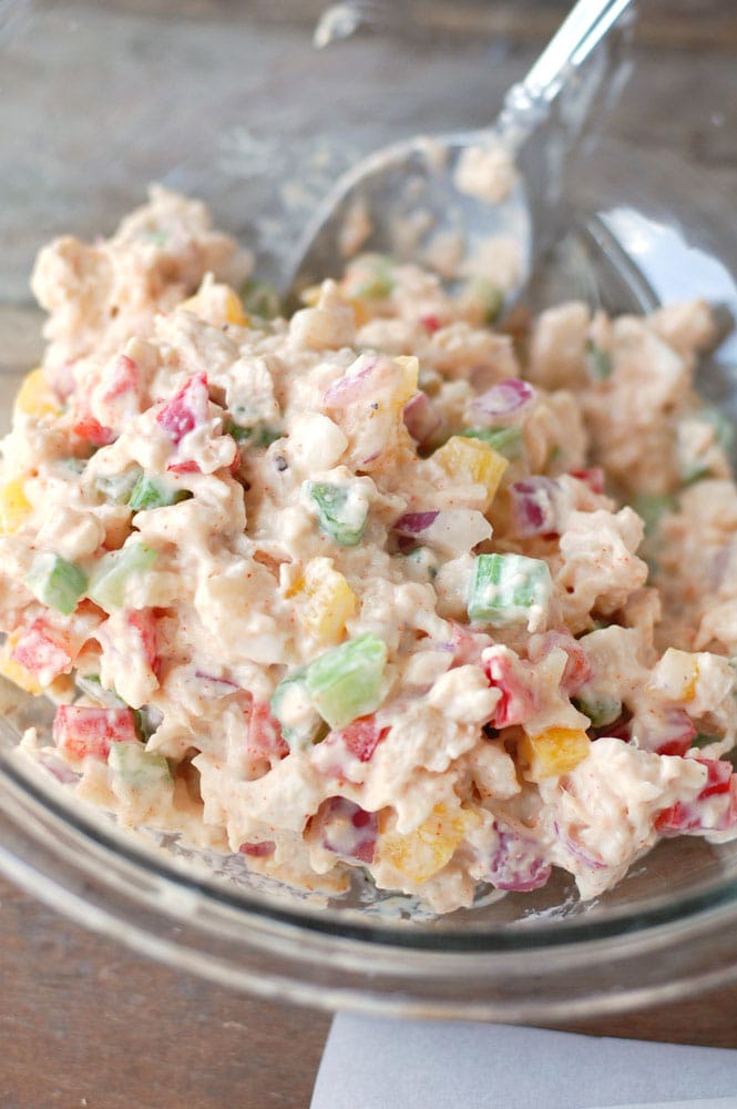 Spicy chicken salad mixed up in a glass bowl with spoon 