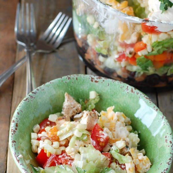 Green bowl with salad and forks off to the side.