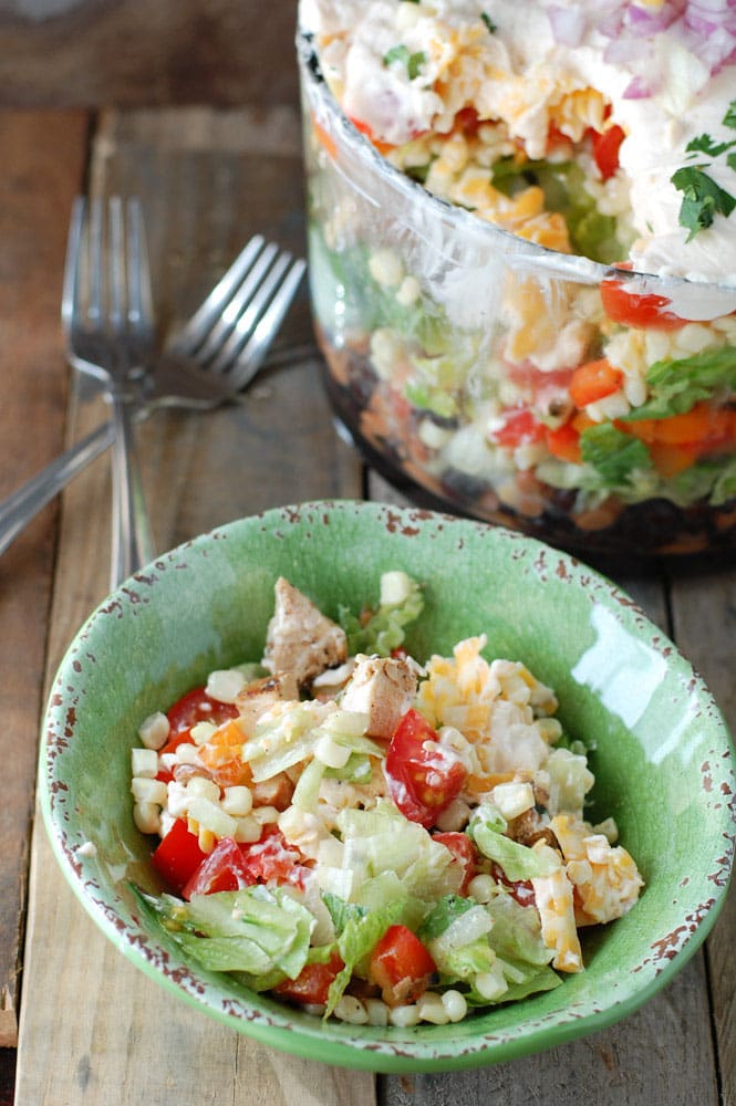 Green bowl with salad and forks off to the side. 