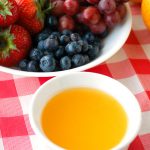 Bowl of orange dip and bowl of fruit.