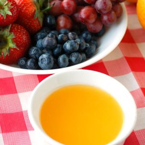 Bowl of orange dip and bowl of fruit.