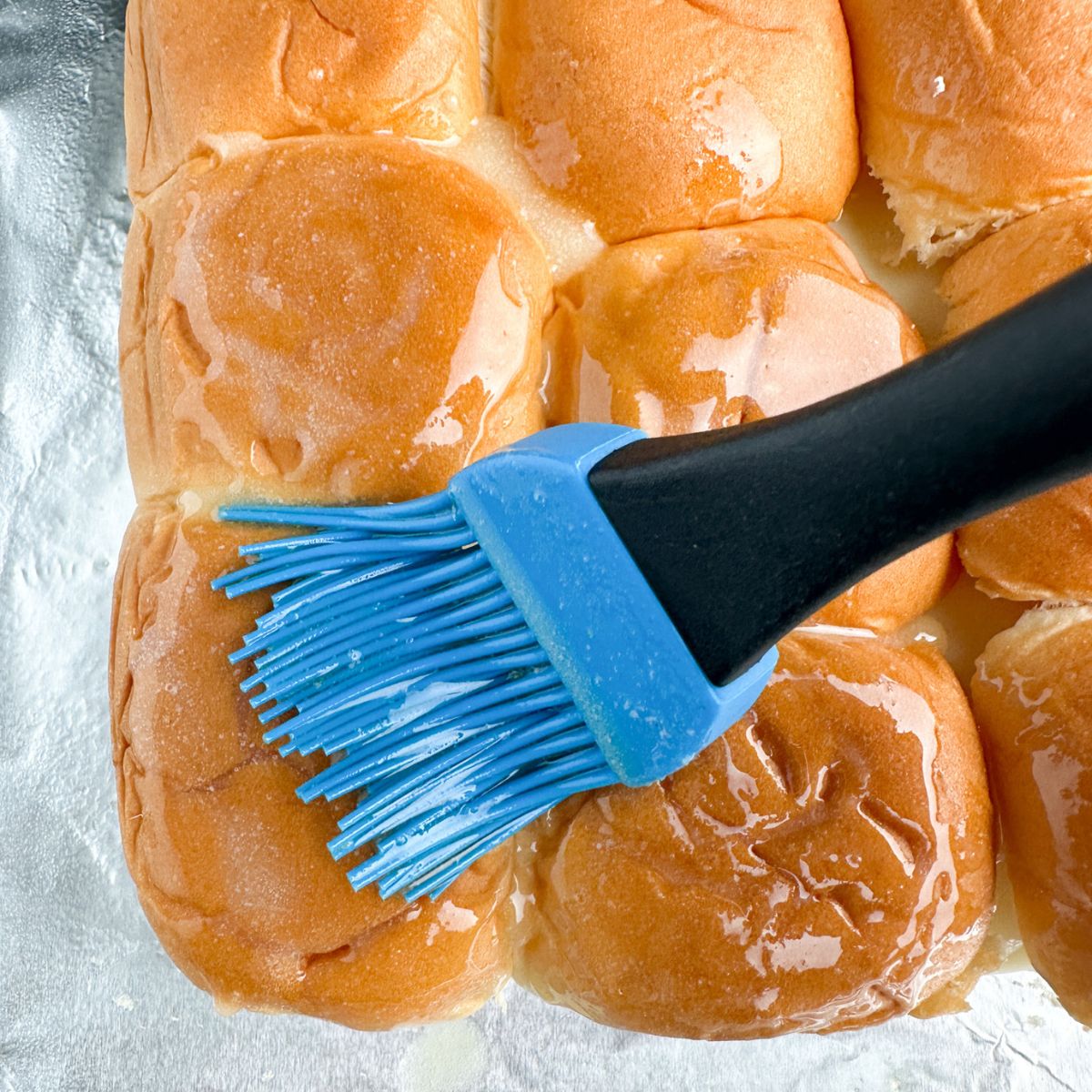 Brushing melted butter over rolls. 