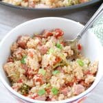 Bowl of quinoa, sausage and onions with a fork.