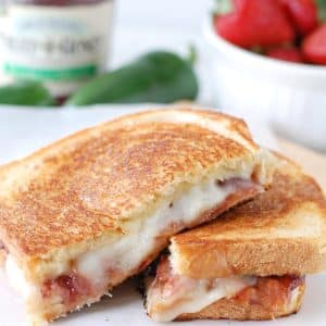 Grilled cheese sandwich cut in half on plate.