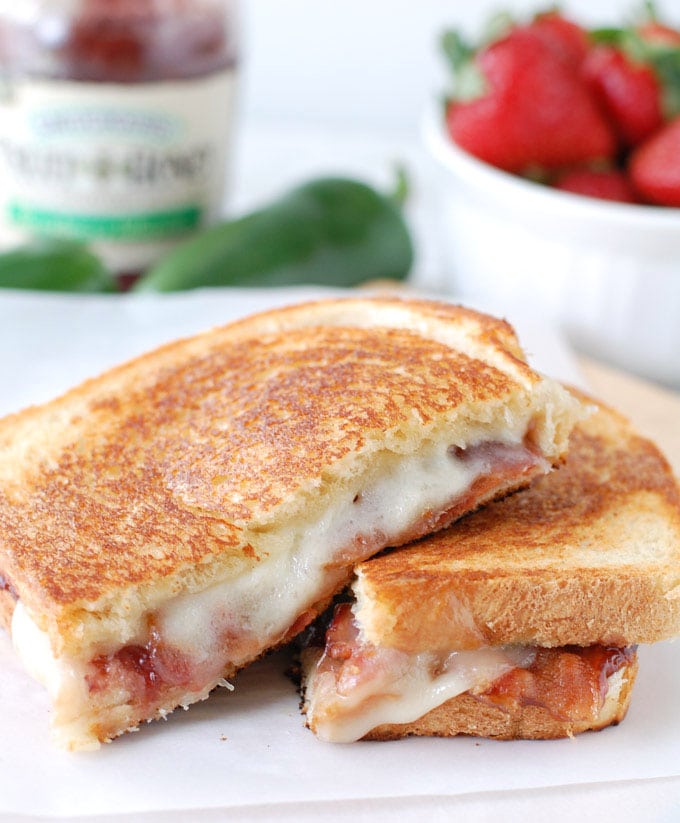 Grilled cheese sandwich cut in half on plate. 