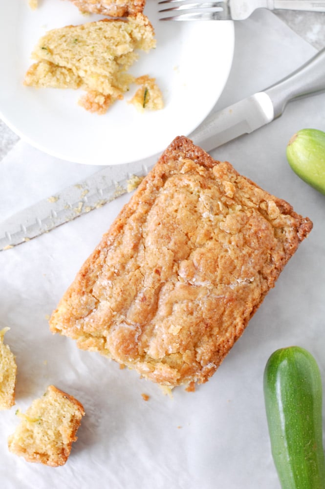 Zucchini Bread Sliced on a table with knife and a plate and fork.