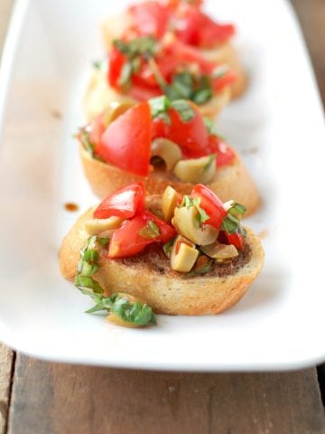 Pieces of bread with green olives and tomatoes.