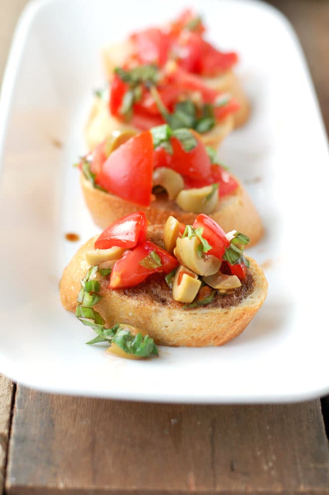 Pieces of bread with green olives and tomatoes. 