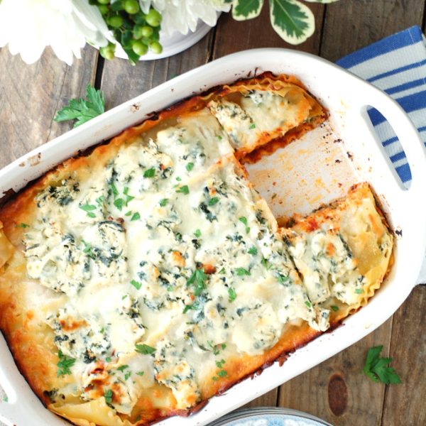 Lasagna in casserole dish with piece missing.
