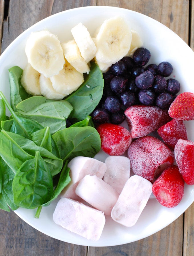 Bowl with spinach, banana, blueberries, strawberries, yogurt cubes