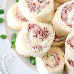 Roast beef tortilla roll-ups stacked on plate.