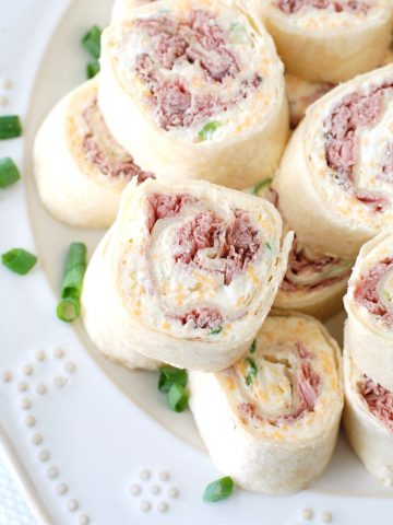 Roast beef tortilla roll-ups stacked on plate.