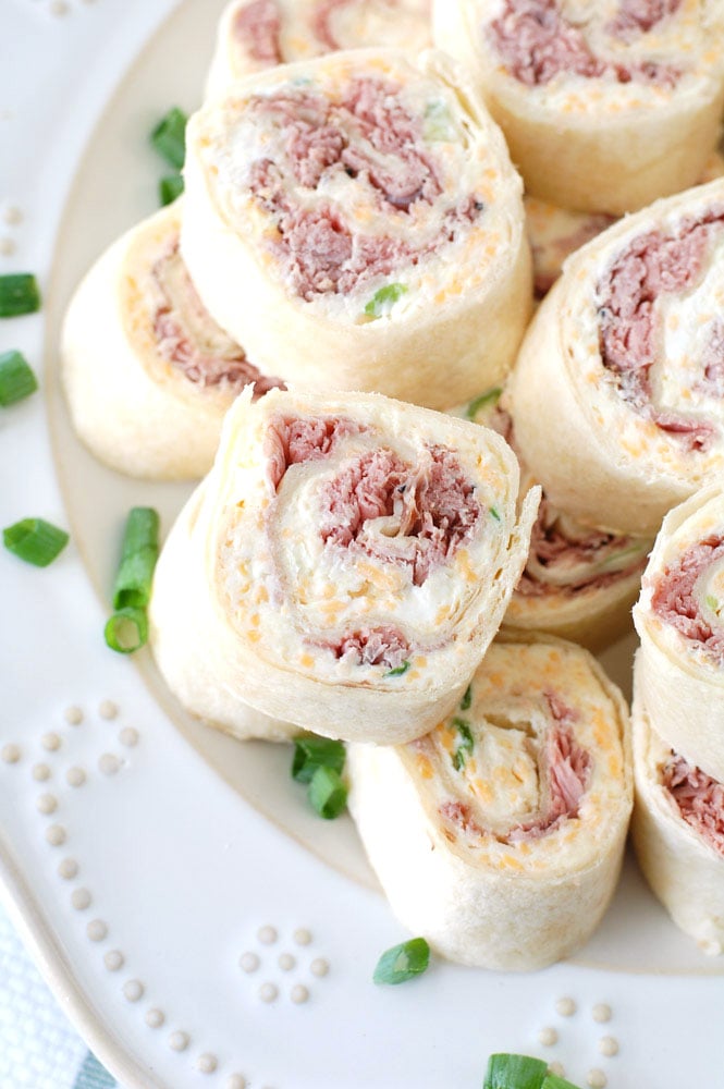 Roast beef tortilla roll-ups stacked on plate. 