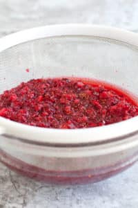 Sparkling cranberry lime mocktail cranberries in a strainer