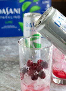 Pouring sparkling water in glass with cranberries