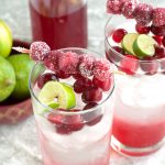 Two glasses with water, cranberries and lime wedge.