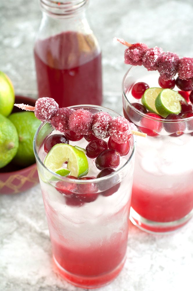 Two glasses with water, cranberries and lime wedge. 