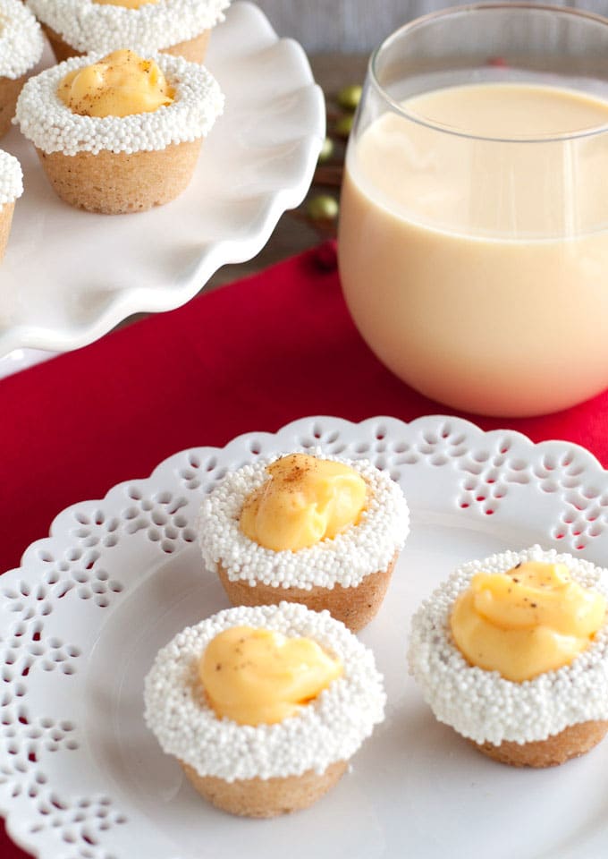 Eggnog cookie cups on a plate with glass of eggnog