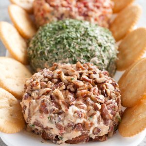 Pecan and chive cheese ball on plate with crackers.