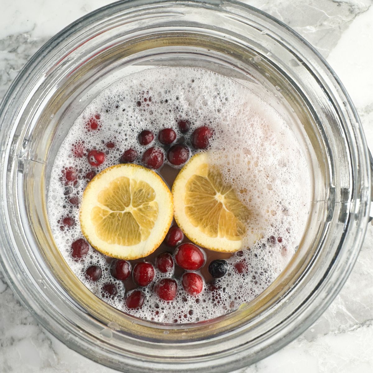 Jar with drink and cranberries and orange slices. 