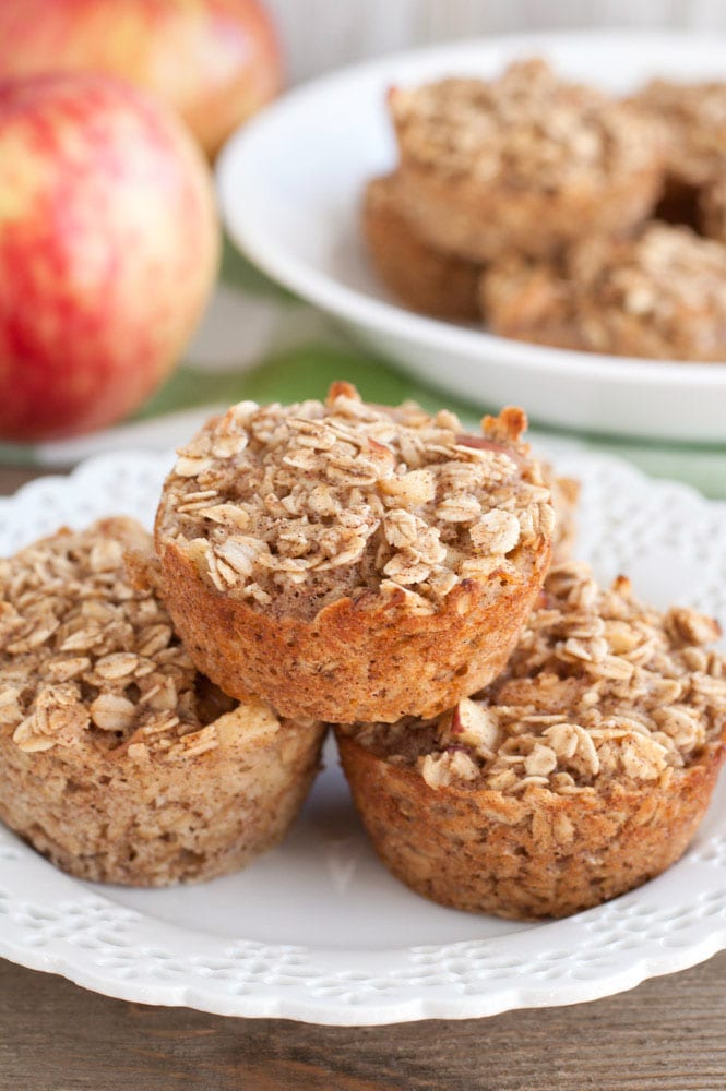 A plate with 3 oatmeal cups and apples in the background. 