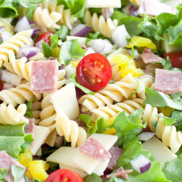 Bowl with lettuce, pasta, tomatoes, salami, cheese and
