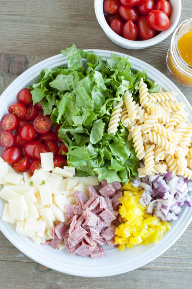 Bowl with lettuce, pasta, tomatoes, cheese, salami, pepper, onion 