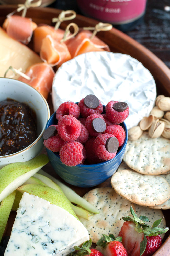 Bowl of raspberries with chocolate chips, crackers, cheese