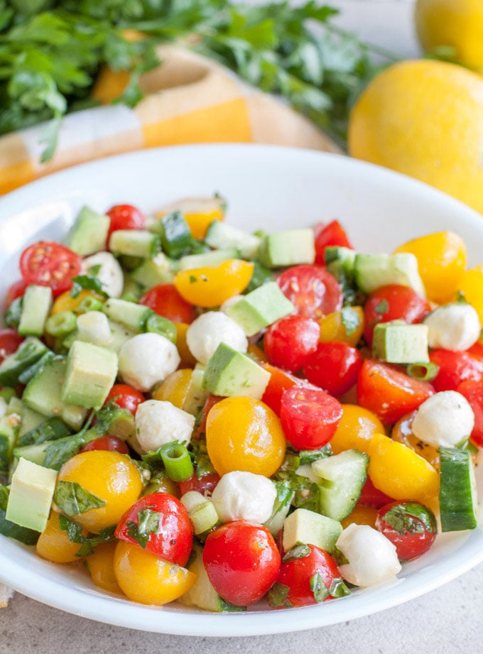 Cucumber Tomato Avocado Salad, a colorful and delicious salad filled with tomatoes, cucumbers, mozzarella cheese, avocado, herbs and lemon dressing.