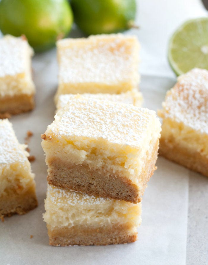 Margarita Bars stacked on top of each other with limes in the background. 