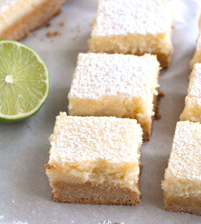 Margarita Bars lined up on parchment paper with a wedge of lime. 