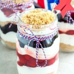 Mason jar with cherry and blueberry trifle wrapped in red, white and blue string.