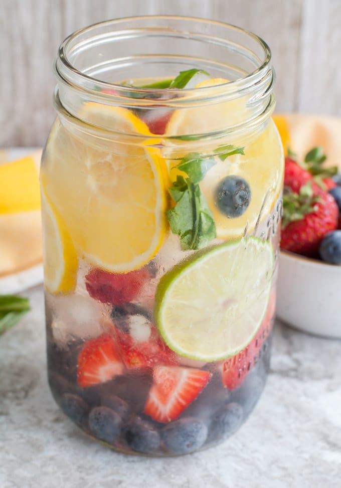 Mason jar glass filled with oranges, strawberries, blueberries, raspberries