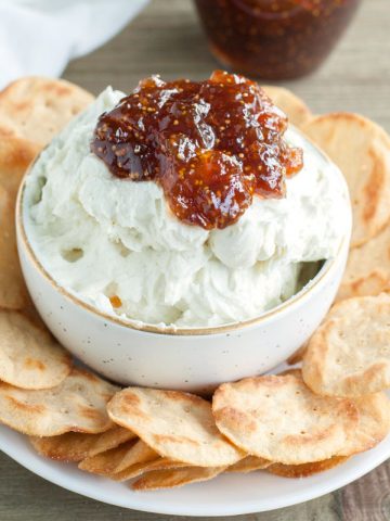 Bowl of whipped goat cheese topped with fig jam.