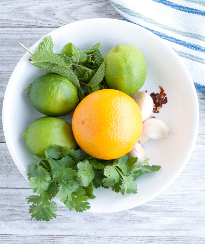 Bowl with orange, mint, cilantro, lime and garlic